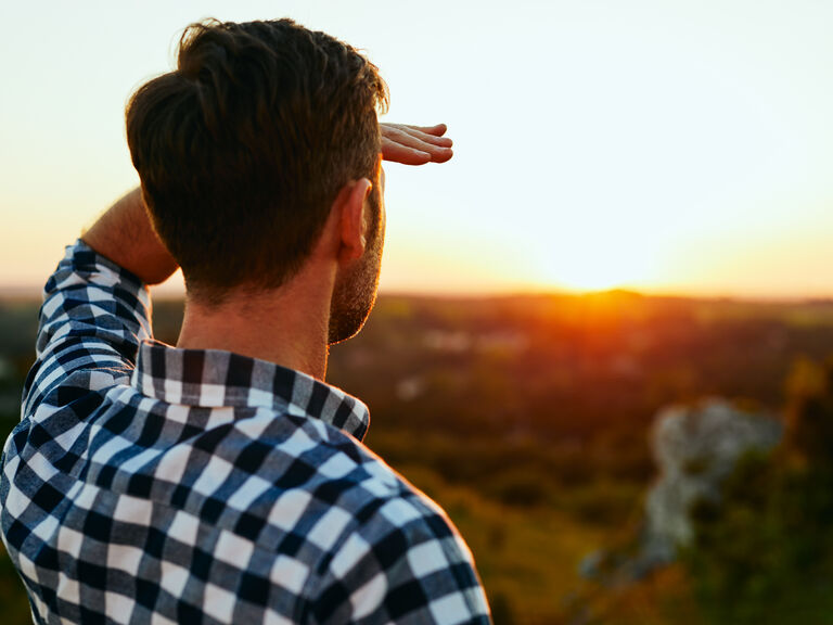 Mann schaut in den fernen Sonnenaufgang